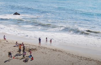 Bathers on a beach, stepping into the sea.