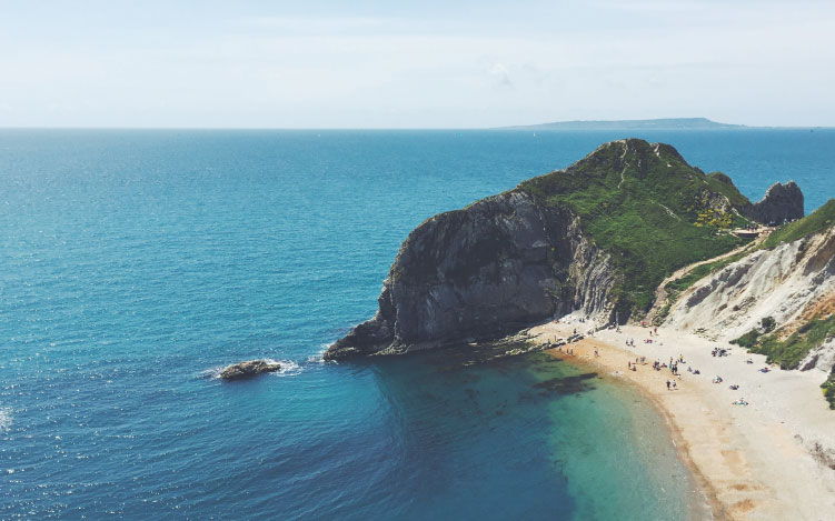 Aerial view of blue sea, sandy beach and rugged rocks