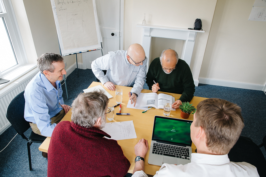 Five colleagues sitting around a table discussing ideas