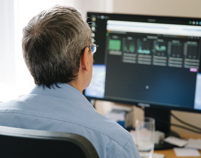 Man sitting at desk looking at data on a computer screen