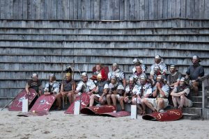 Group of men dressed as Roman soldiers sitting in amphitheatre